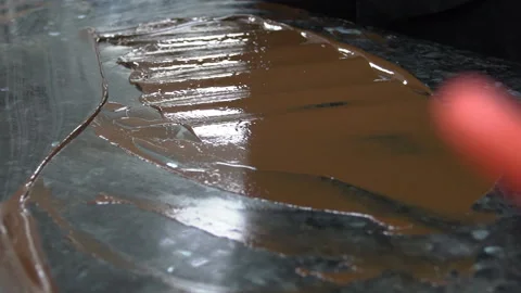 Young cook distributes chocolate mass on table surface indoors. Stock Footage 85620581