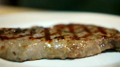 Young cook puts rosemary branches on fried meat in kitchen of restaurant. Stock Footage 87322853