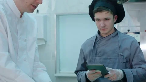 Young cook trainee with tablet asking chef questions about cooking process Vídeos de archivo 72326805