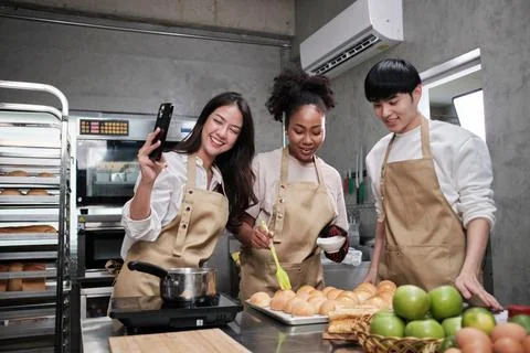 Young cooking class students enjoy, taking selfie photos in the kitchen. Stock Photos