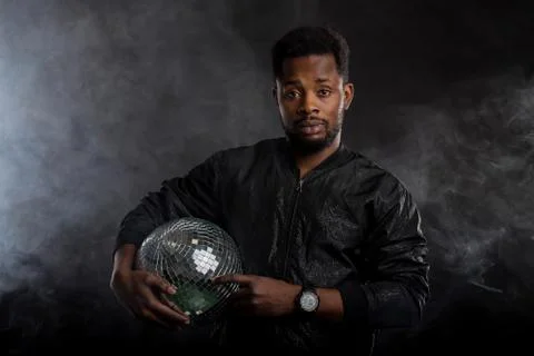 Young cool black man with disco ball over black background Stock Photos