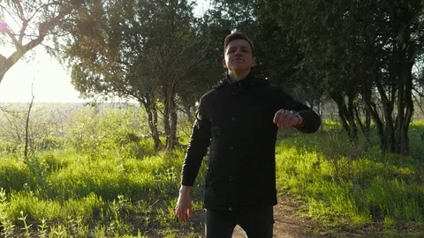 Young cool guy goes confidently through the beautiful park on sunset. Green Vidéo 106730606