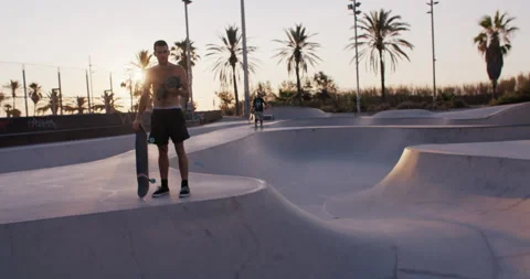 Young cool man on skateboard in pool at sunset Video stock 211328244