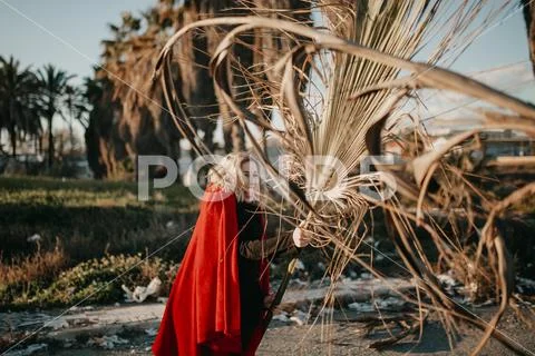 Young cool woman playing and battling with palm tree branches outdoors. Stock Photos