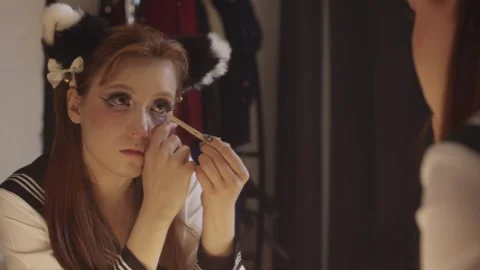 Young cosplayer applying eye makeup in mirror Stock Footage 317436702