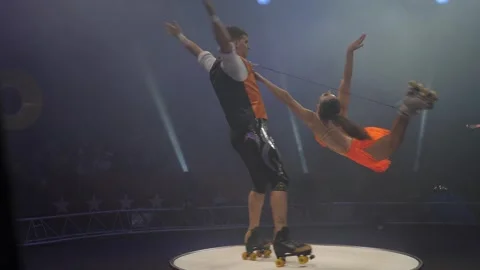 A young couple of acrobats on roller skates perform in a circus. Stock Footage 311796769