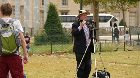 A young couple and a man taking pictures in a park in Paris Stock Footage 59964814
