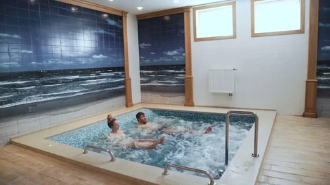 Young couple are having fun in the swimming pool Jacuzzi, bubbles, relaxation Stock Footage 75501079