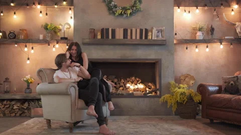 A Young Couple Are Smiling Hugging Sitting On A Chair Are At Home Stock Footage 138017262
