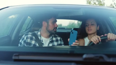 Young couple arguing while driving a car, using navigation on phone Slow motion Stock Footage 274424428
