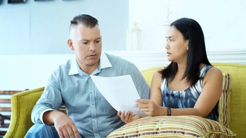 Young couple arguing while reading document in the living room Stock Footage 92194380