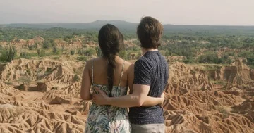 Young couple with arms around each other overlooking dry desert scenery Stock Footage 86101155