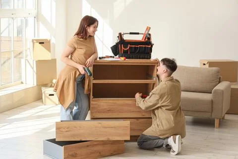 Young couple assembling chest of drawers at home Stock Photos