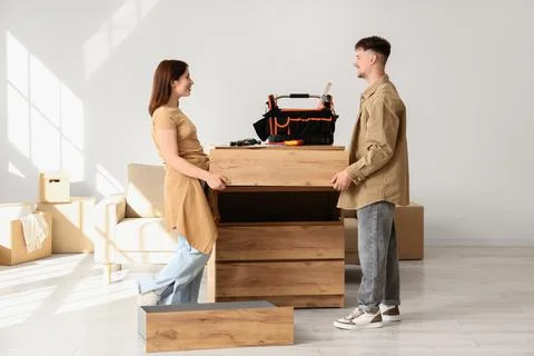 Young couple assembling chest of drawers at home Stock Photos