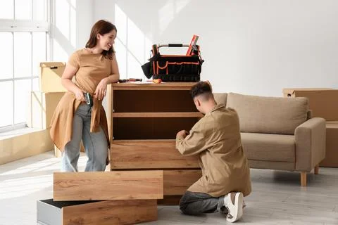 Young couple assembling chest of drawers at home Stock Photos