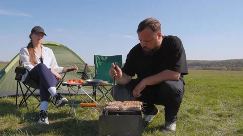 Young couple barbecuing meat during camping trip Видео 344606635