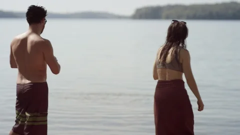 A young couple in bathing suits skip rocks on a hot summer day in slow motion Stock-Footage 116754170