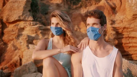 Young Couple On The Beach Watching Sunset With Protective Face Mask Stock Footage 136595865