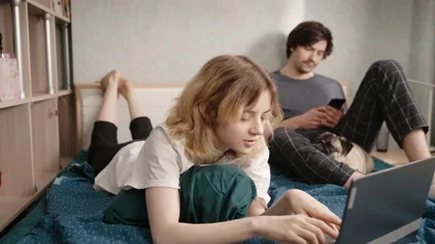 Young couple in bed making a video call with someone via laptop Stockbeeldmateriaal 197489554
