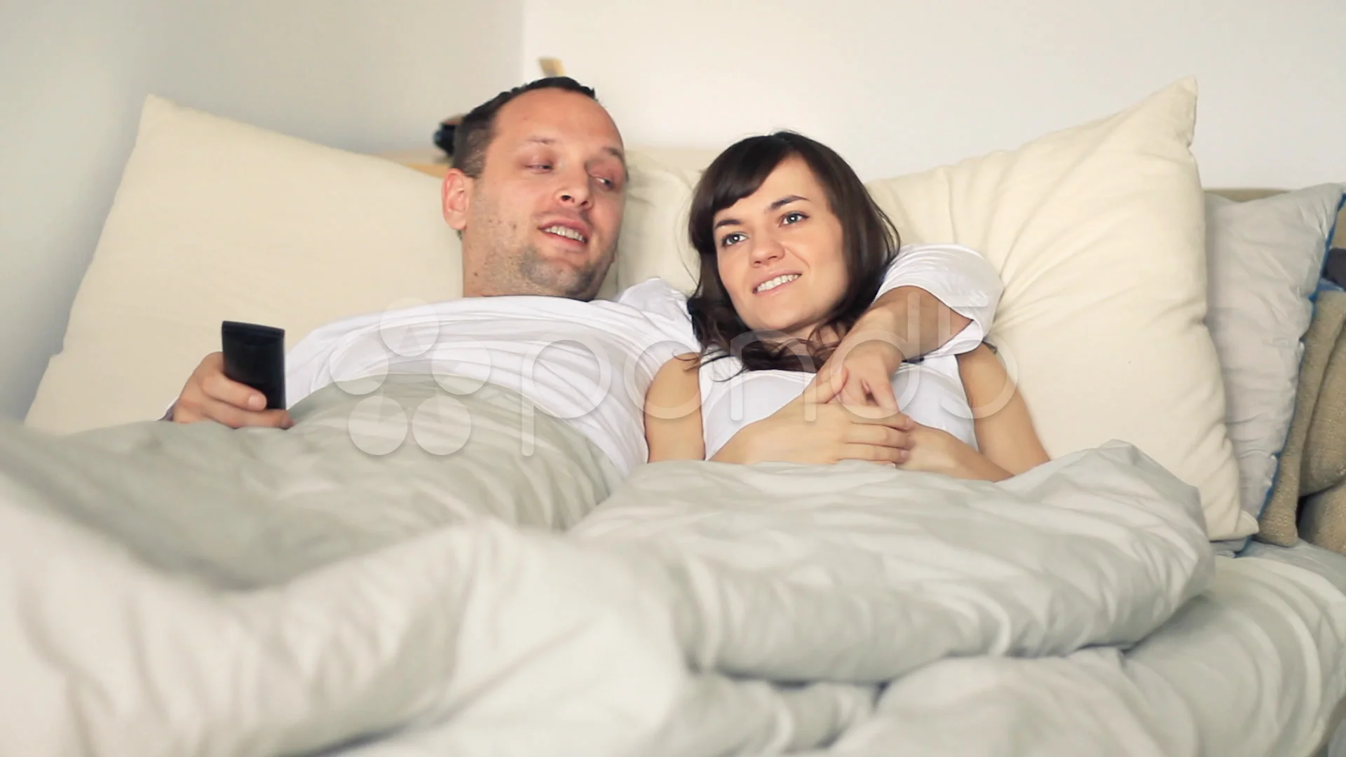 Young couple in bed watching tv HD