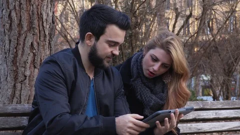 Young couple on a bench at the park using tablet  Stock Footage 74697688