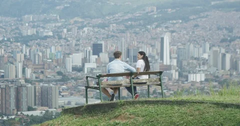 Young couple on bench playing and overlooking city skyline Stock Footage 86149596