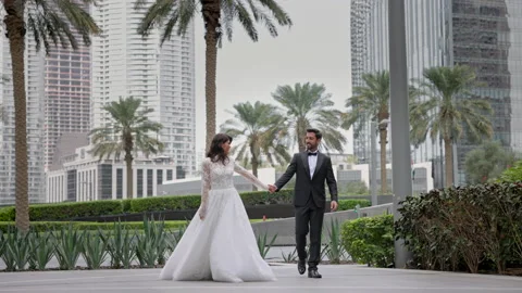 Young Couple Of Brides Walking Down The Street In Dubai Holding Hands. Wonderful Vídeos de archivo 153732726