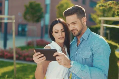 Young couple browsing on digital tablet outdoors Stock Photos