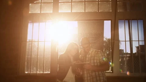 Young couple browsing the internet or online shopping in cafe with sun flare at Stock Footage 199632249