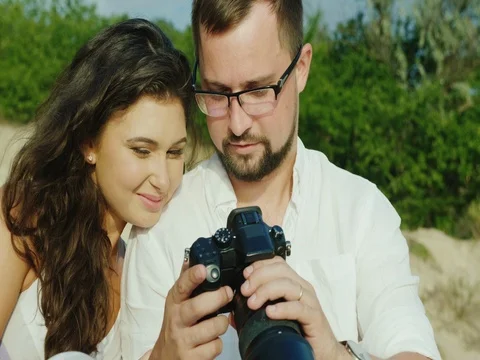 Young couple browsing photos on a digital camera. Sit side by side, huddled Stock Footage 80078358