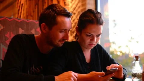 Young couple in cafe browsing internet on smart phone Video stock 97534711