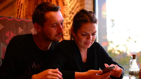Young couple in cafe browsing internet on smart phone Stock Footage 97536014
