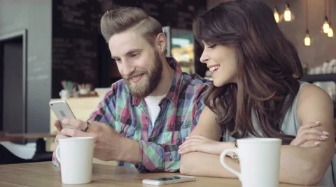 Young couple in cafe browsking internet on smart phone Stock Footage 64654132