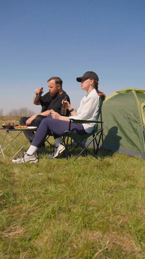 Young couple camping and grilling food outdoors Stockbeeldmateriaal 344606165