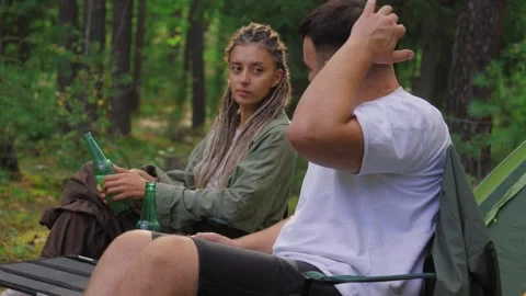 Young couple camping in forest drinking beer and talking Stock Footage 327527671