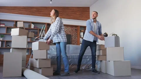 Young couple carrying boxes in new apartment on moving day.New accommodation or Stock Footage 268763034