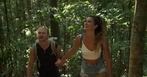 Young couple caucasian with backpack trail up tropical forest with sun flares.  Stock Footage 152014077