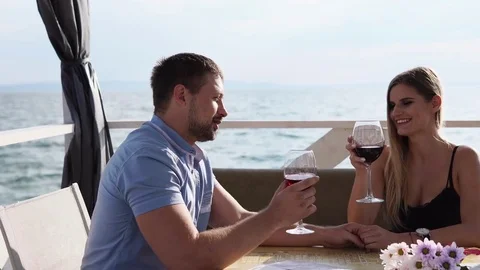 A young couple celebrate their anniversary in a restaurant with an open veranda Stock Footage