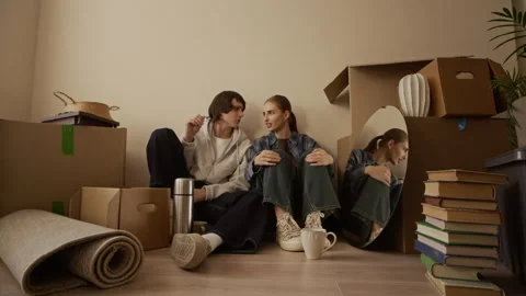 Young Couple Chatting among Boxes in New Apartment on Moving Day Stock Footage 331581321