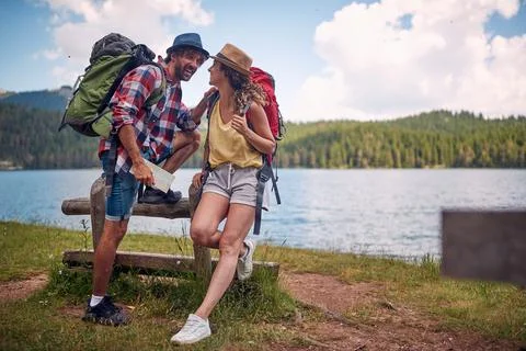A young couple is chatting while making a break at the lake during hiking t.. Stock Photos