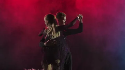 Young couple cheerfully dancing jive on a smoky background with crimson Stock Footage 139008006