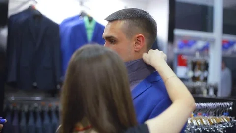 Young couple choose a jacket in the store. Loving guy and girl buy clothes in 스톡 동영상 75965406