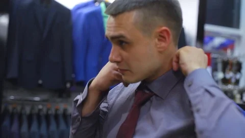 Young couple choose a jacket in the store. Loving guy and girl buy clothes in Stock Footage 75966383
