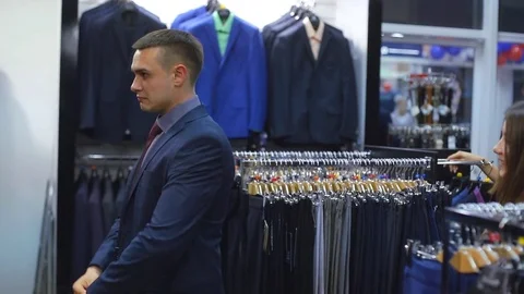 Young couple choose a jacket in the store. Loving guy and girl buy clothes in Stock Footage 75967866