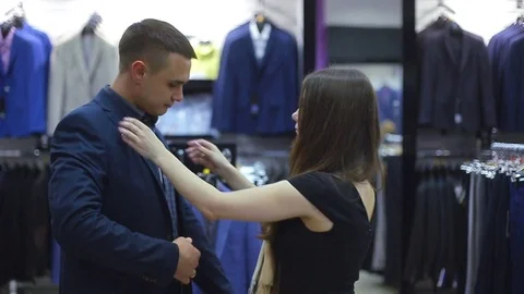 Young couple choose a jacket in the store. Loving guy and girl buy clothes in Stock Footage 76531510