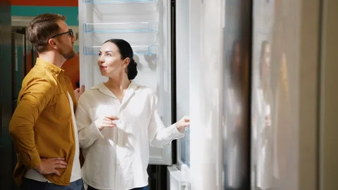 Young couple chooses a fridge in a consumer electronics store for new home Stock Footage 279593260