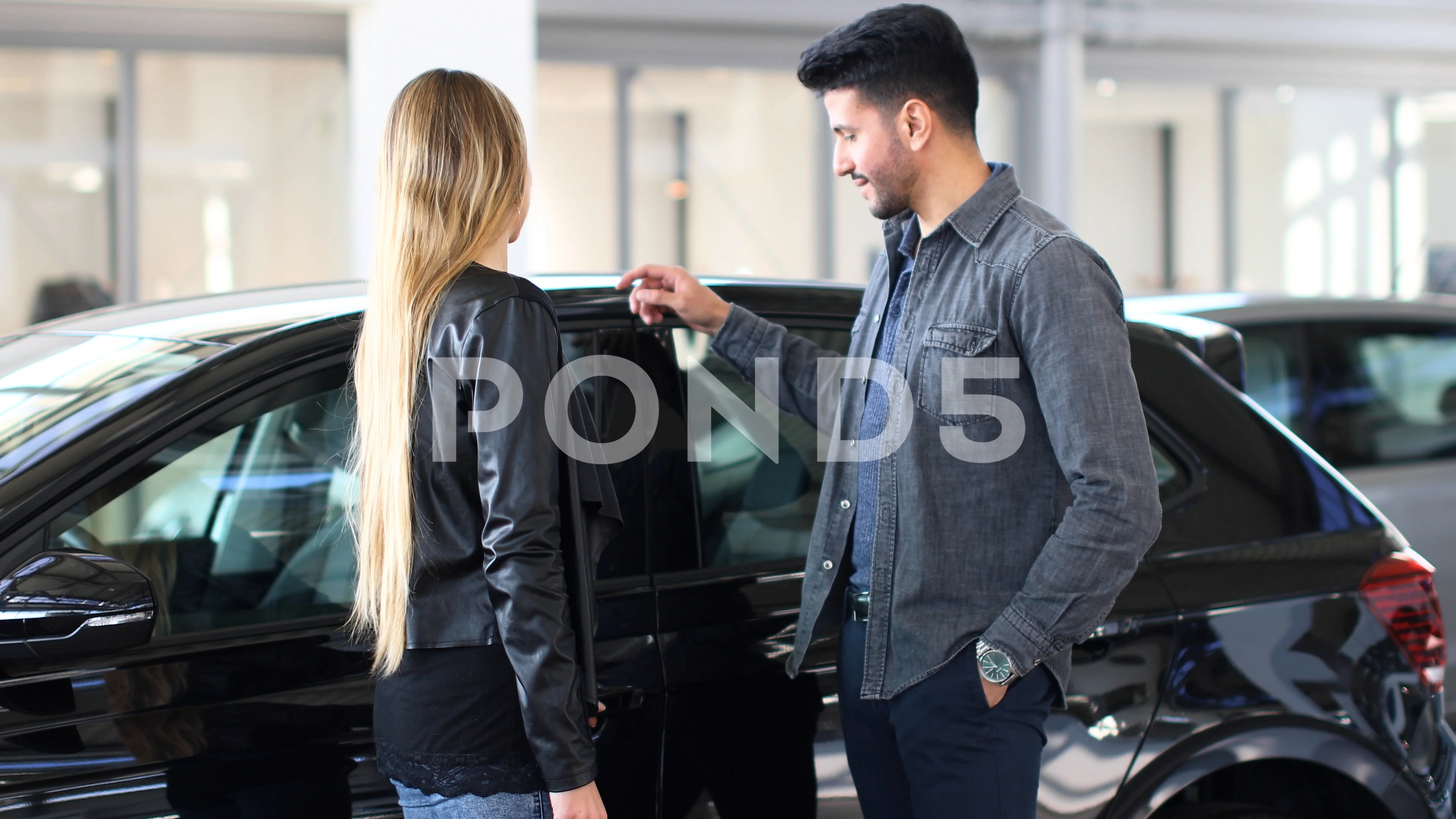 Young couple choosing new car for buying in dealership shop