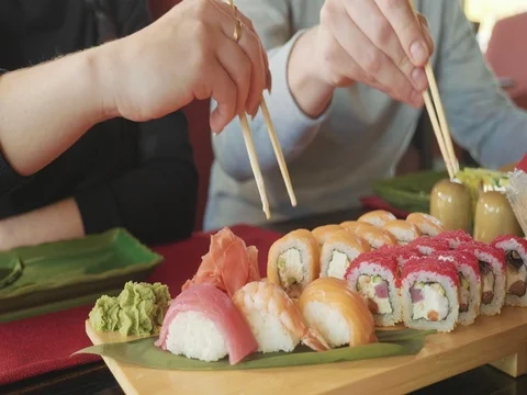 Young couple with chopsticks takes sushi from a plate in a japanese restaurant. Stock Footage 82832853