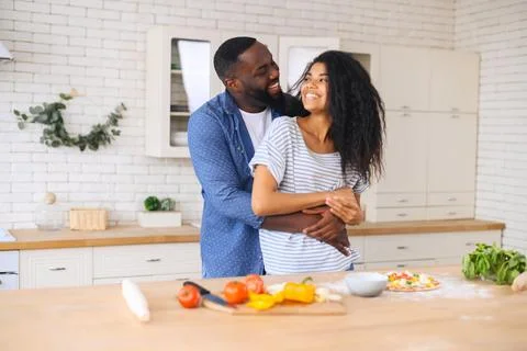 Young couple cooking and hugging in the kitchen Stock Photos