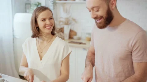 Young couple cooking together preparing dinner and talking at home Stock Footage 146277230